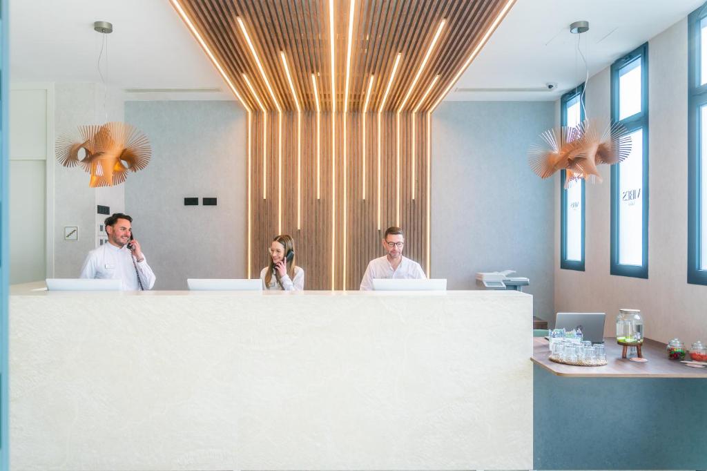 three people standing behind a counter in an office at Hotel Málaga Vibes in Málaga