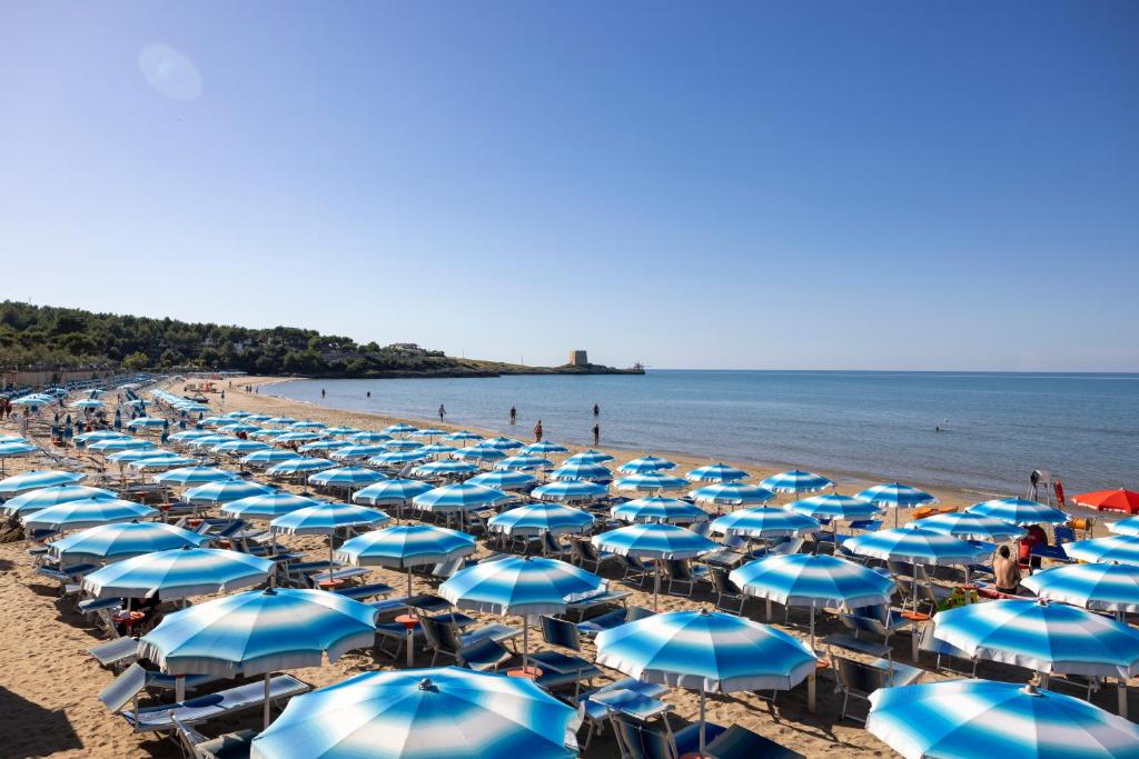 a bunch of blue and white umbrellas on a beach at Paglianza Hotel in Peschici