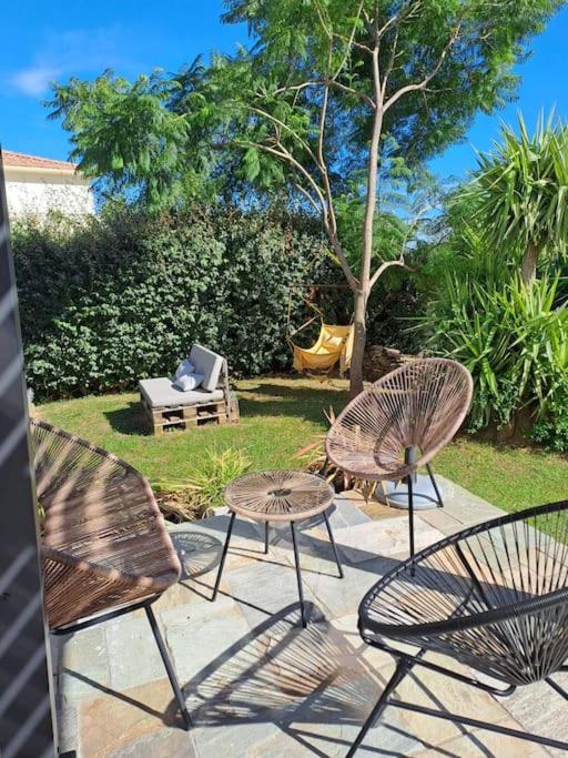 un groupe de trois chaises, une table et un banc dans l'établissement Appartement T2 rez-de-villa, à Furiani