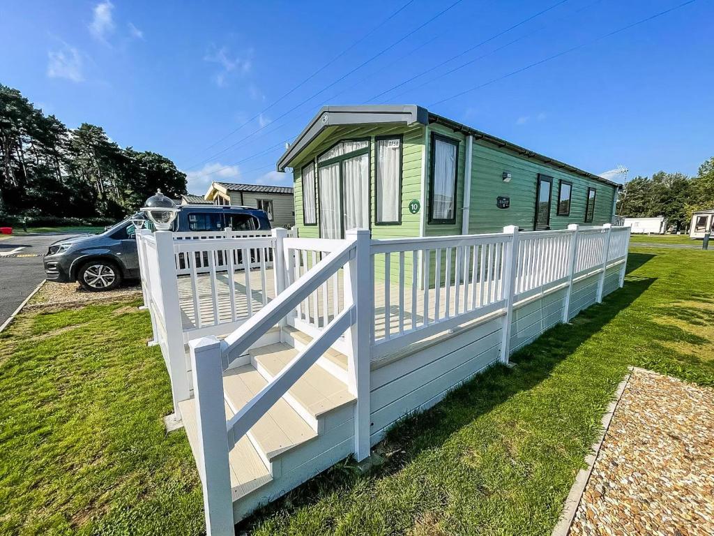 a green and white house with a white fence at Lovely 6 Berth Caravan At Caldecott Hall Country Park, Norfolk Ref 91010C in Great Yarmouth