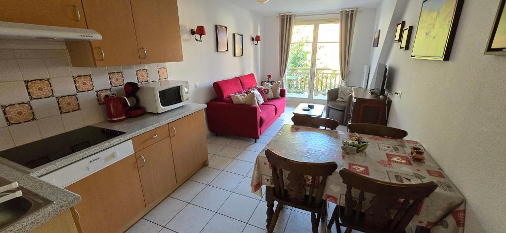 a kitchen with a table and chairs and a living room at Le Petit Nid in Bergheim