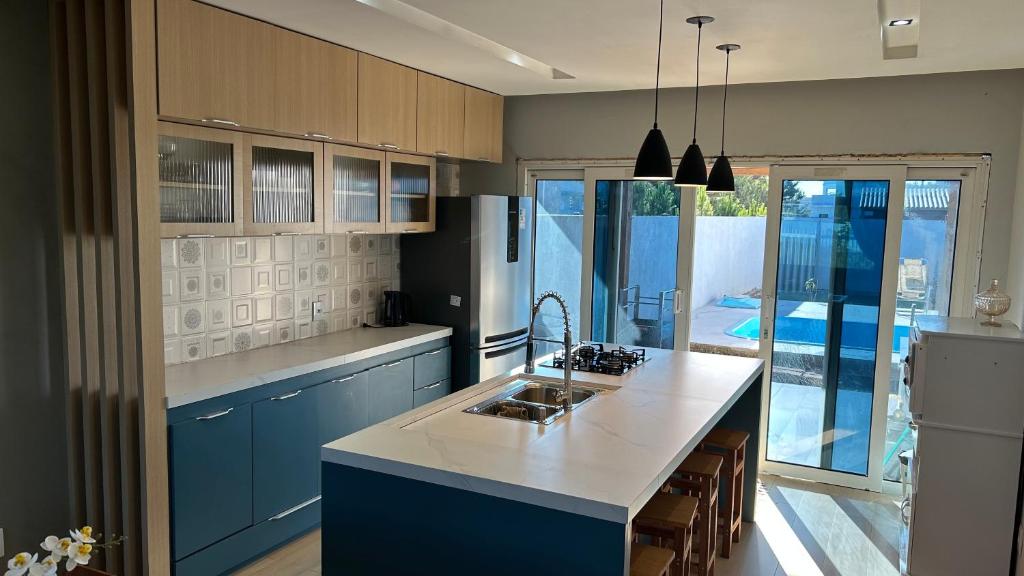a kitchen with blue cabinets and a white counter top at Casa piscina MAJU in Imbé