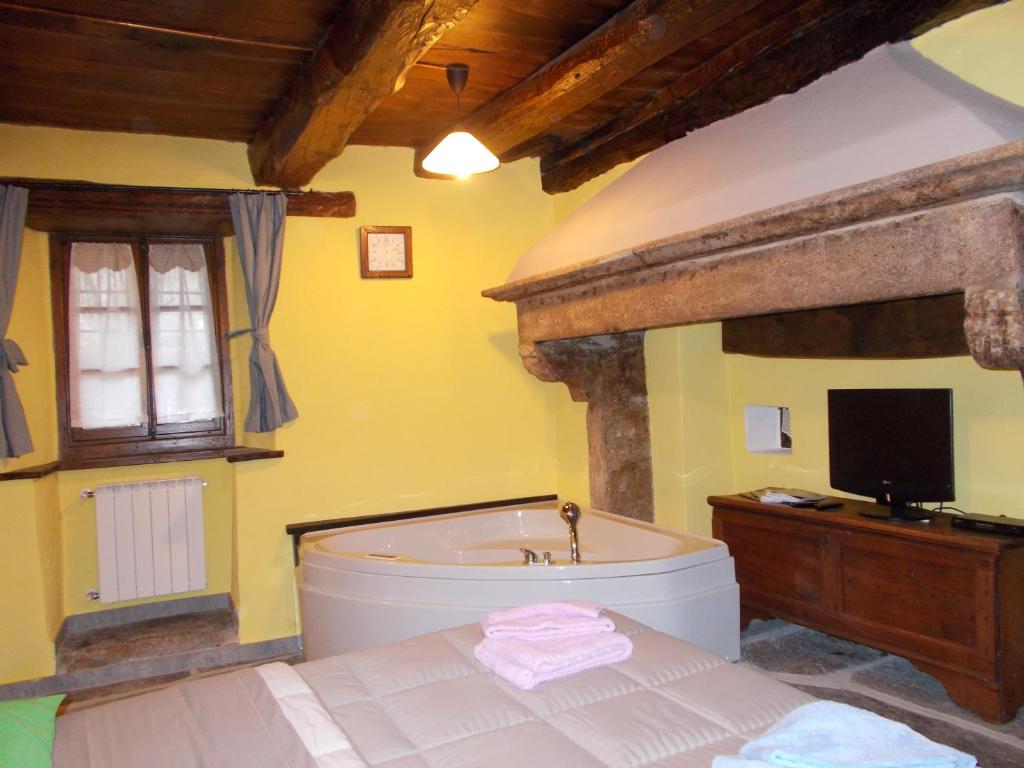 ein Schlafzimmer mit einer Badewanne und einem TV in einem Zimmer in der Unterkunft Il Borgo Di Monica in Domodossola