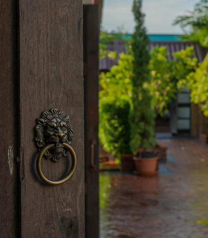 a bronze door knocker on a wooden door at Standard in Ban Phrom Min