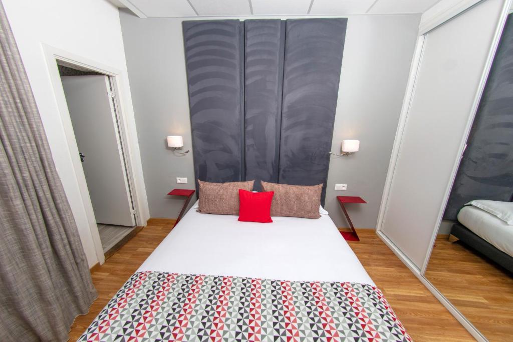 a small bedroom with a bed with a red pillow at Hôtel Méditerranée in Calvi