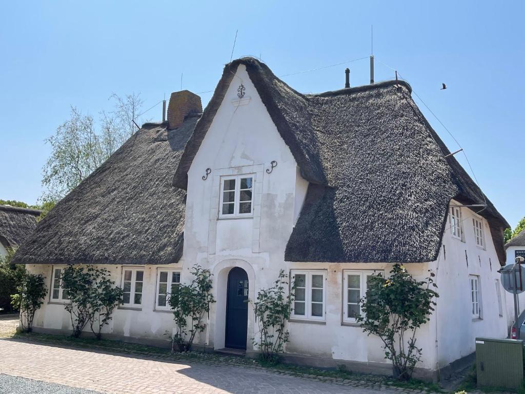 a white house with a black roof at Kapitänshaus von 1712 - neu saniert in Nieblum