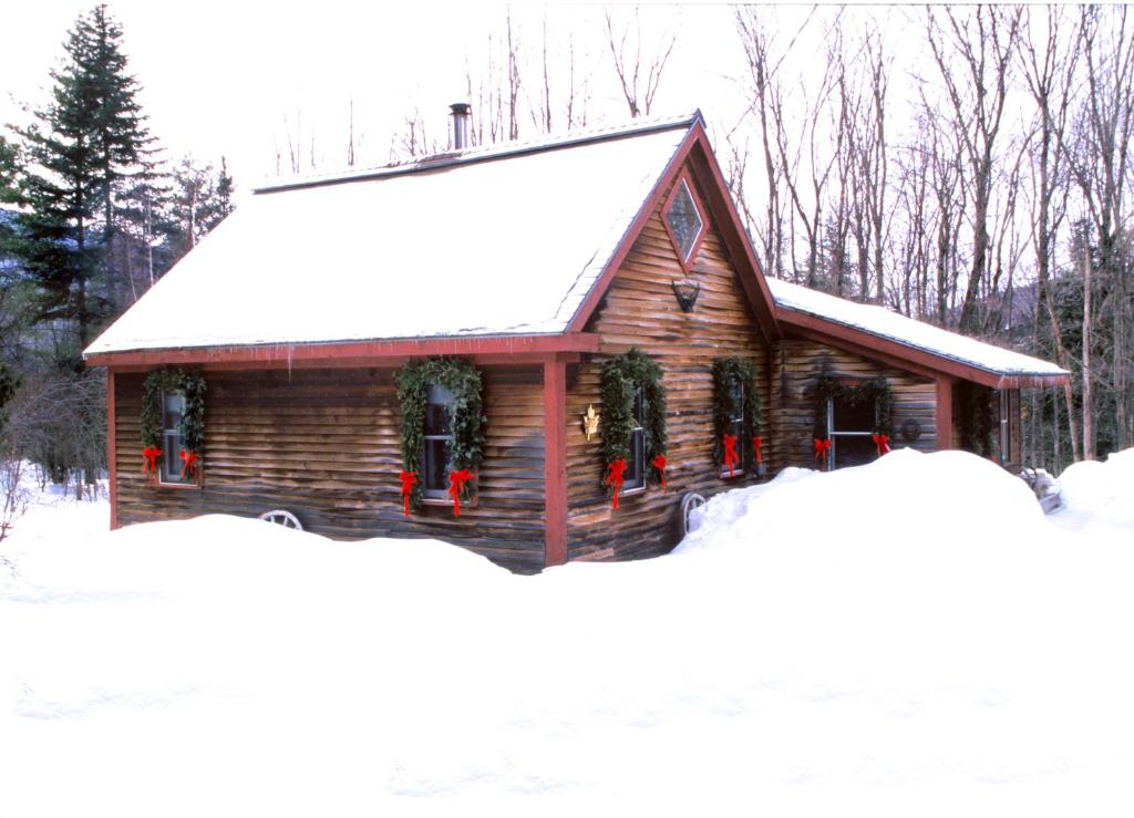 a log cabin with christmas wreaths on it at Goldilocks Cabin in Stowe