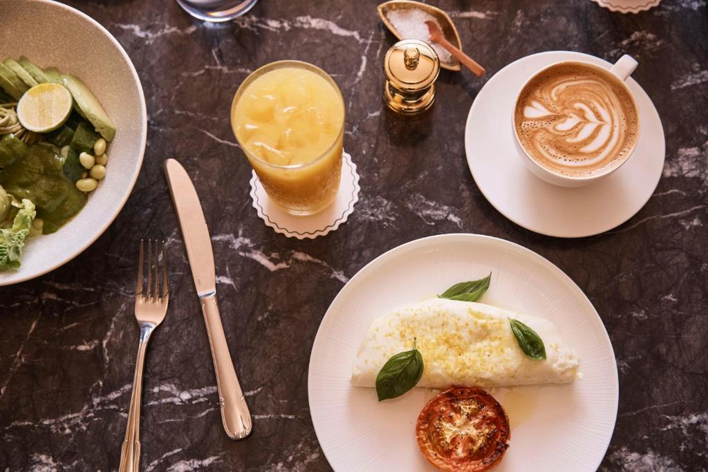 a table with plates of food and a cup of coffee at QT Singapore in Singapore