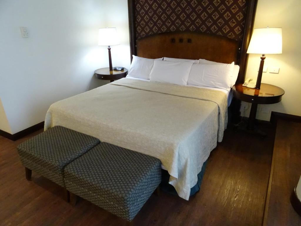 
a hotel room with a bed, chair, and nightstand at Abasto Hotel in Buenos Aires

