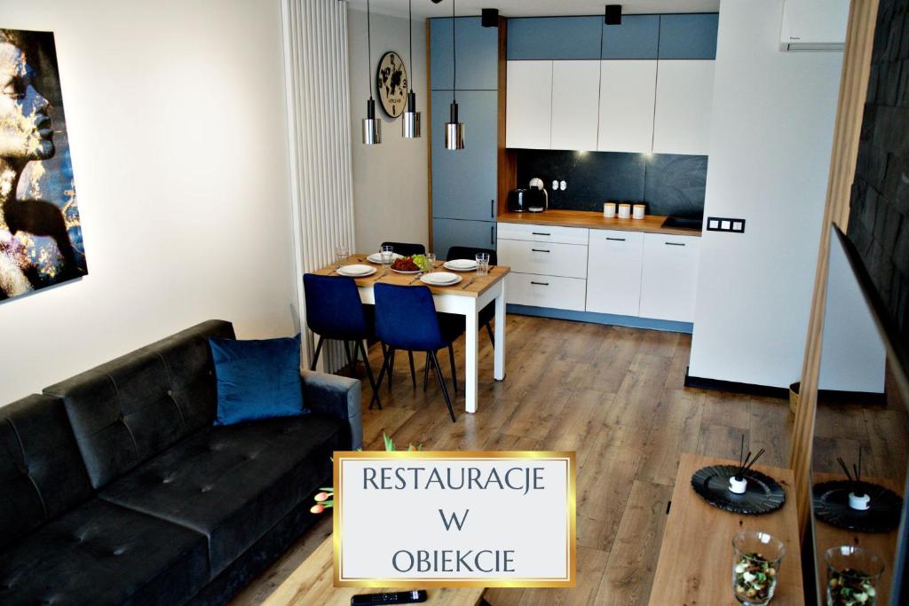 Una sala de estar con un sofá negro y una cocina. en Apartment Bulwary 4, en Oświęcim