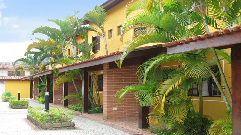 un edificio amarillo con palmeras delante en Residencial Doce Marina en Caraguatatuba