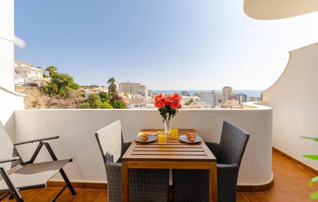 a table with chairs and a vase of flowers on a balcony at Gå nemt til Fuengirola strand, restauranter, butikker, padel og meget mere! in Las Lagunas Mijas