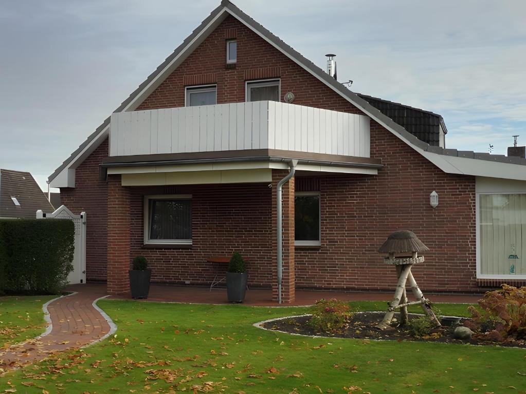 une maison en briques rouges avec une statue dans la cour dans l'établissement Ferienwohnung Neumann, à Wesselburen