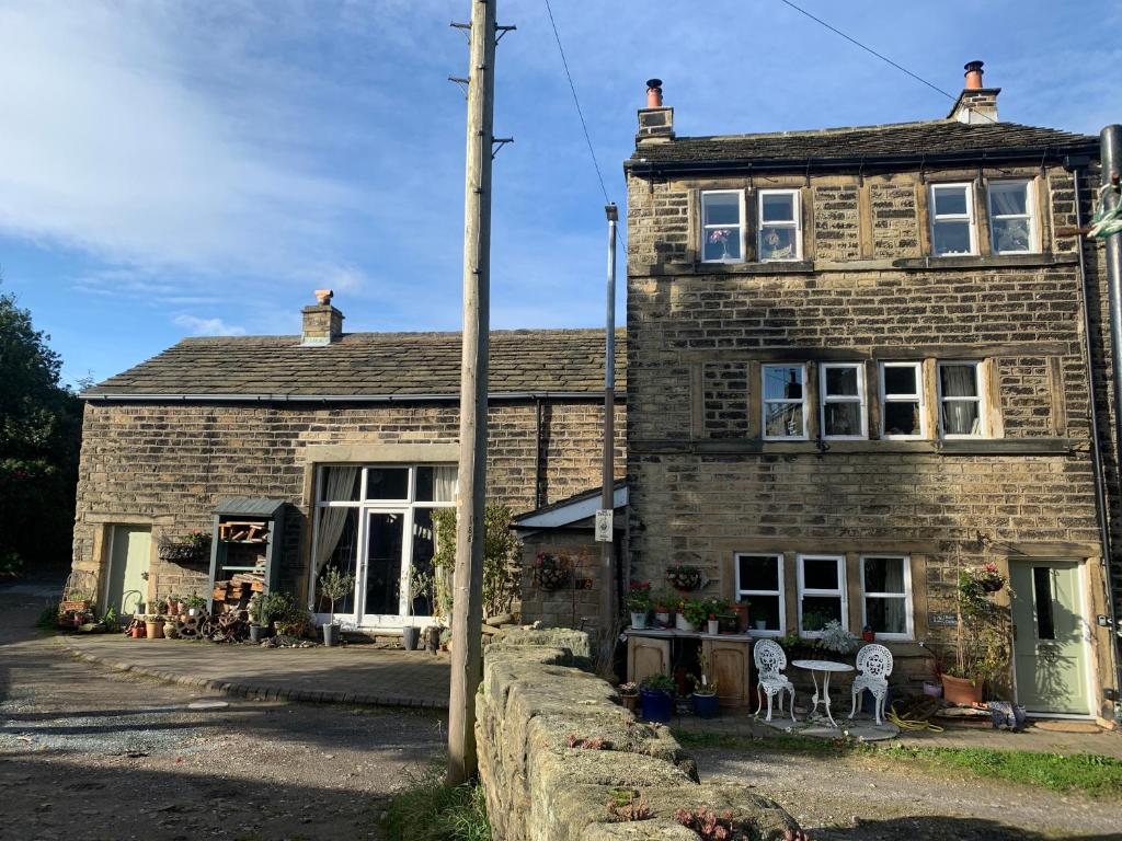 una vieja casa de ladrillo con dos sillas delante en Barn Cottage Quirky Weaver's Cottage in Quaint Hamlet, en Holmfirth