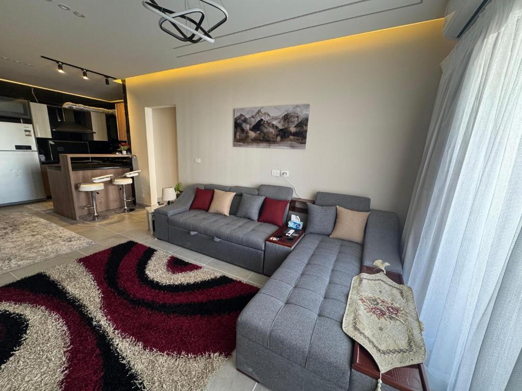 a living room with a gray couch and a kitchen at Celia -1 Bedroom Beauty in Madīnat al Amal