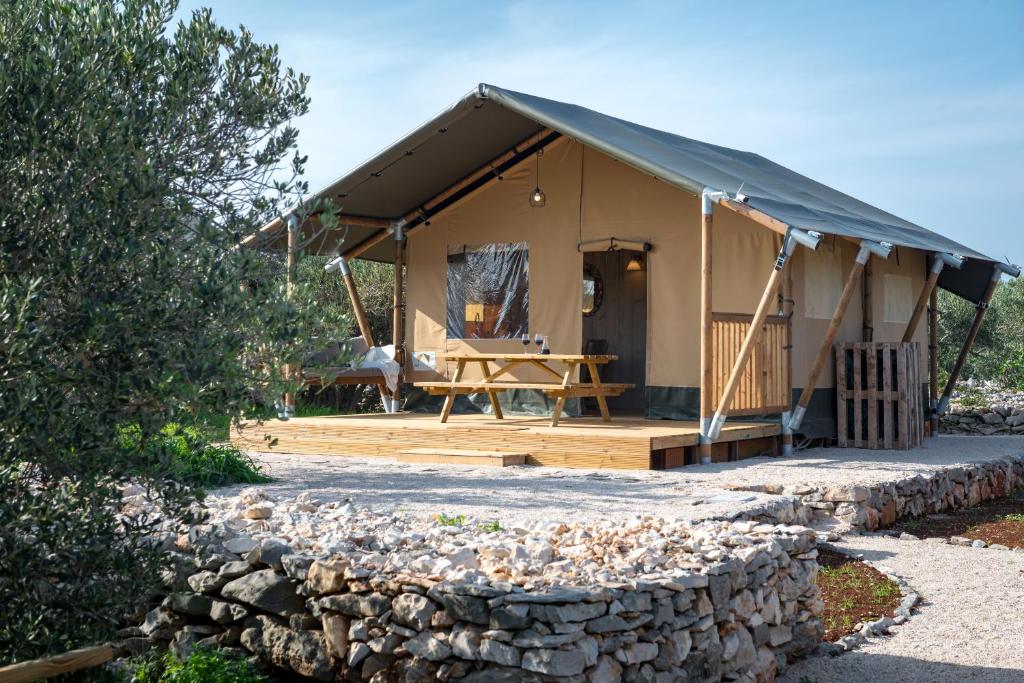 ein Zelt mit einem Tisch und einer Steinmauer in der Unterkunft Adriatic Heritage Glamping No2 with Jacuzzi in Donje Selo na Šolti