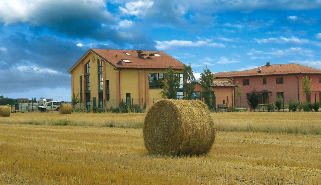 a field with hay bales in front of a house at Il Bucchio Country Hotel in San Giovanni in Persiceto