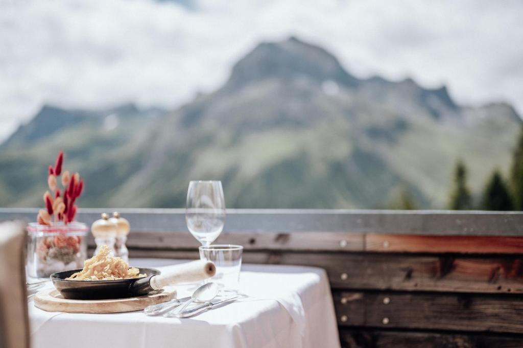 a table with a plate of food and wine glasses at Hotel Goldener Berg in Lech am Arlberg