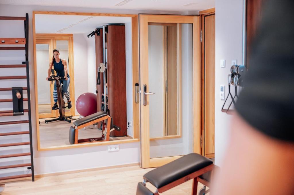 a woman standing in front of a mirror in a gym at Hotel Goldener Berg in Lech am Arlberg