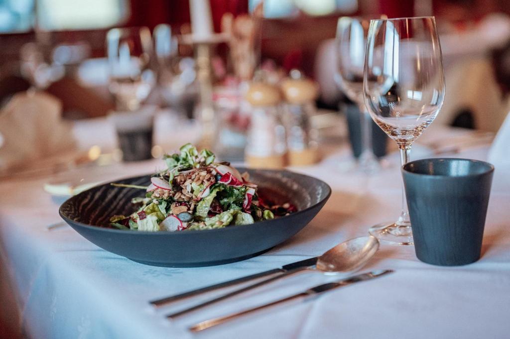 a bowl of salad on a table with a wine glass at Hotel Goldener Berg in Lech am Arlberg