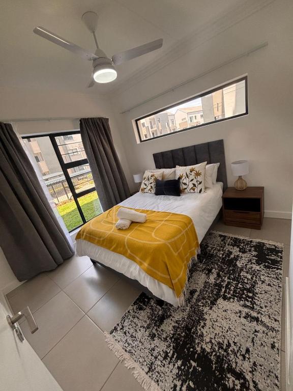 a bedroom with a bed with a yellow blanket on it at Ballito Village 446 in Ballito