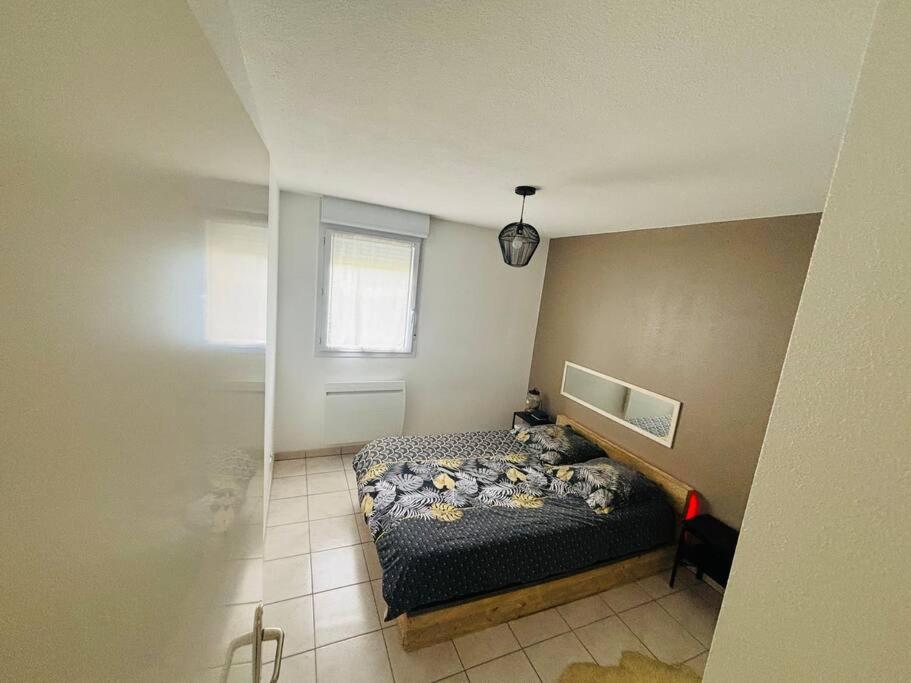 een kleine slaapkamer met een bed en een raam bij Appartement in Millau