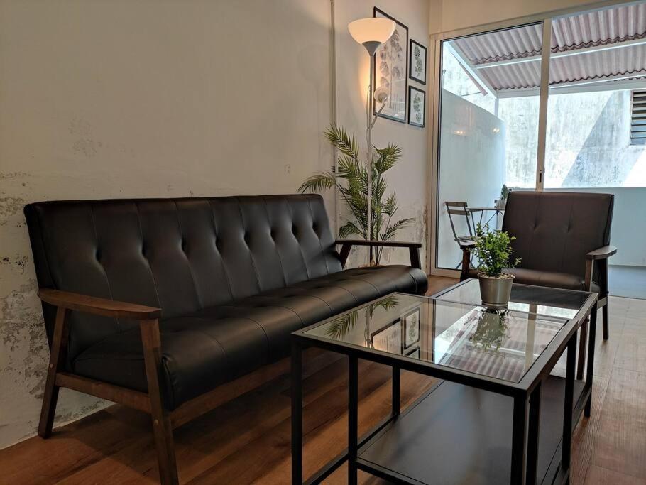 a living room with a leather couch and a table at Heritage House 2BR in Town walkto UNESCO Site & StreetArt 45 in George Town
