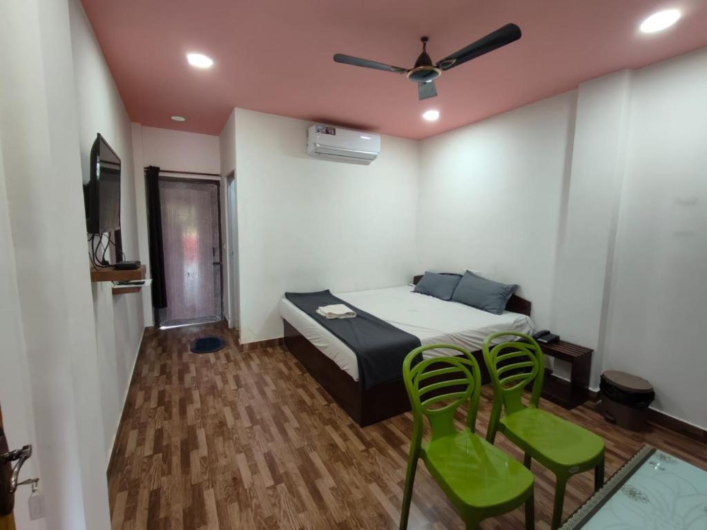 a bedroom with a bed and two green chairs at Kalapani Nest in Port Blair