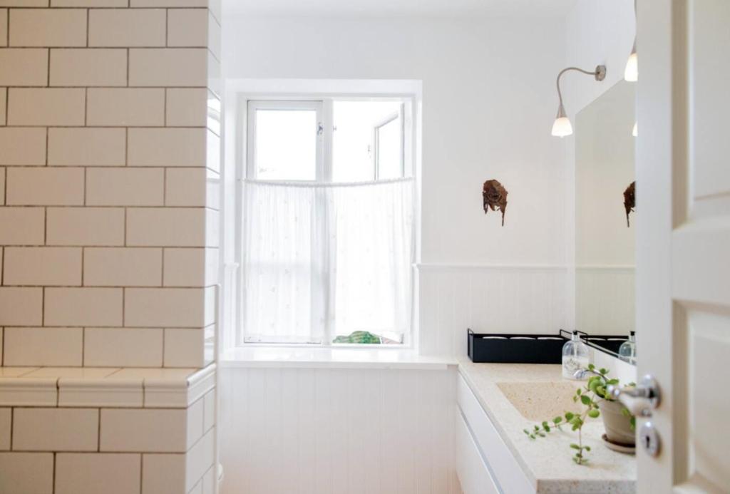 bagno bianco con vasca e finestra di Gertruds Petit Hotel a Odense