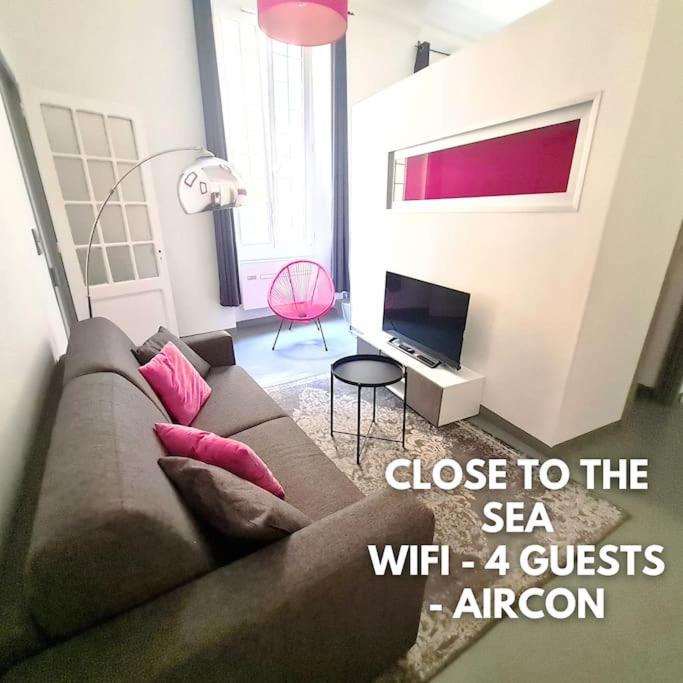 un salon avec un canapé et une télévision dans l'établissement Cosy appartement, moderne, fuchsia, industriel, à Nice