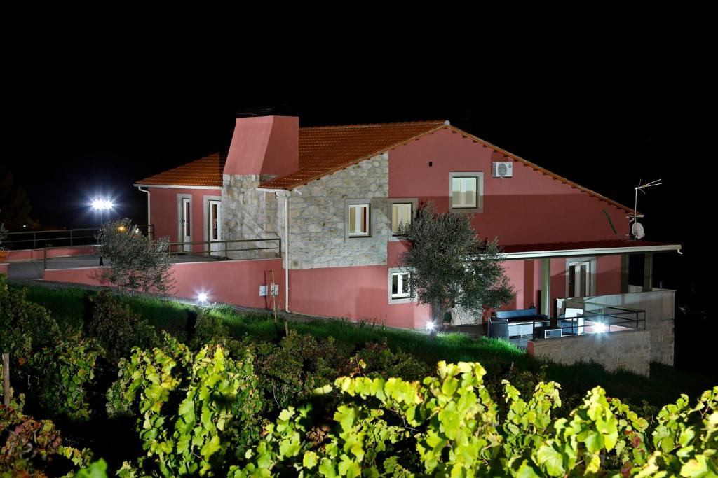 uma grande casa vermelha à noite com uma vinha em Olhares do Douro em Foz do Sabor