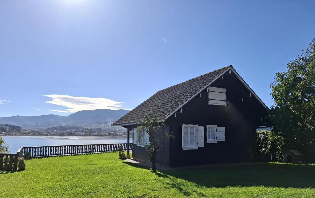 a black house on the shore of a lake at Casa de madera sobre el mar in Nigrán