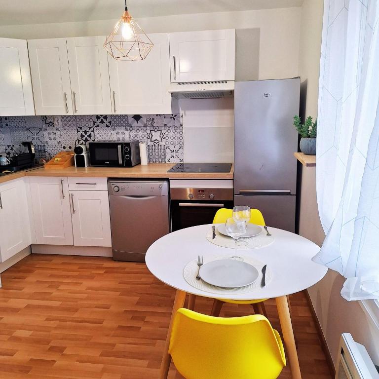 une cuisine avec une table blanche et des chaises jaunes dans l'établissement Le Fatsia - Rennes Gare T2, à Rennes