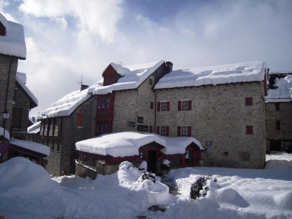 een gebouw bedekt met sneeuw en met sneeuw bedekte daken bij Hotel Casa Escolano in El Pueyo de Jaca