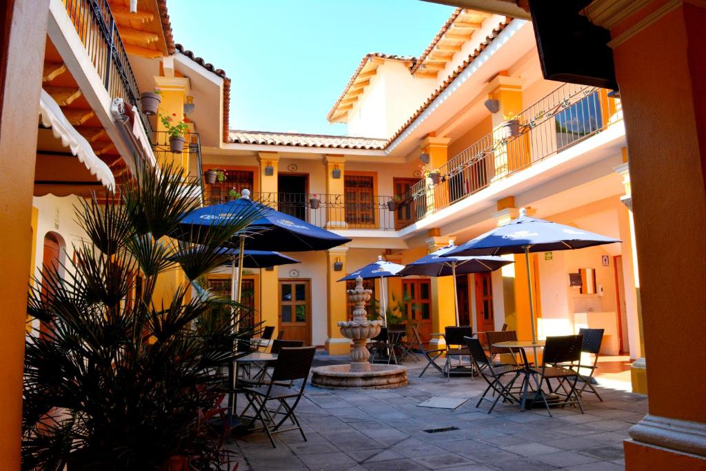 une cour avec des tables, des chaises et des parasols dans l'établissement Hotel Aldama, à Colima