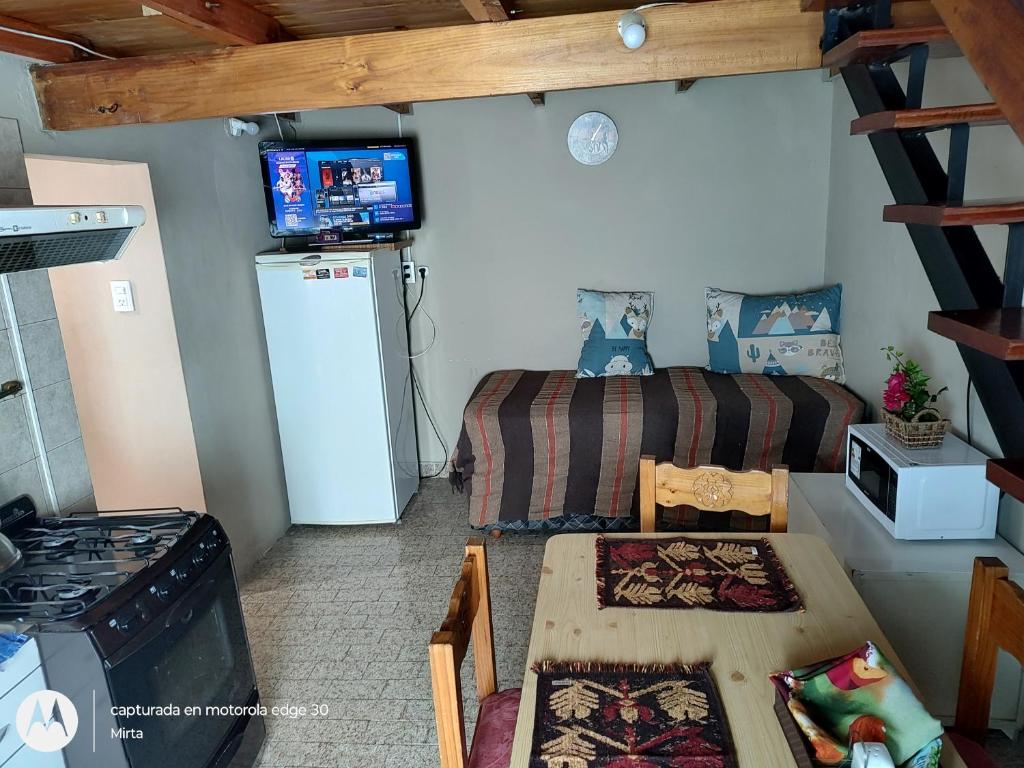 a small room with a bed and a table and a kitchen at El depto de mirta 964 Esquiu in San Bernardo