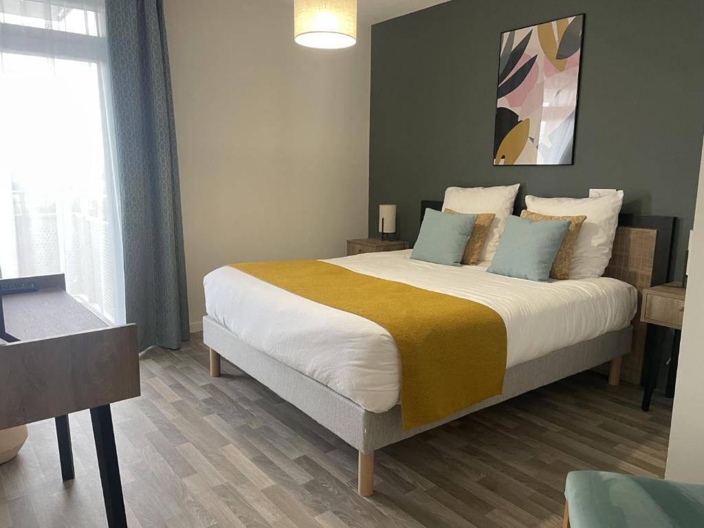 a bedroom with a large bed with blue pillows at Résidence Domitys Pèira Ròsa - Toulouse Purpan in Toulouse