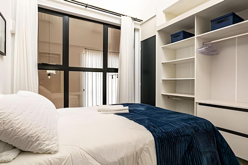 a bedroom with a white bed and a large window at Loft moderno e espaçoso no centro de Floripa -UN30 in Florianópolis