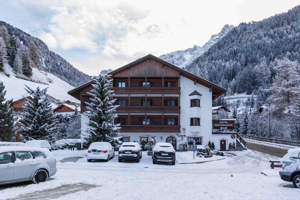 snow covered buildings and a car parked in front of a ski lodge at Hotel Casa Alpina - Alpin Haus in Selva di Val Gardena