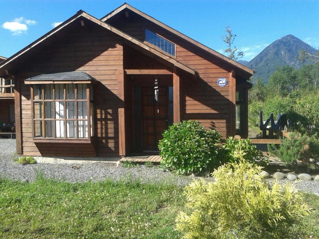 Cabaña de madera con puerta grande y montaña en Cabañas Bosques del Claro, en Pucón