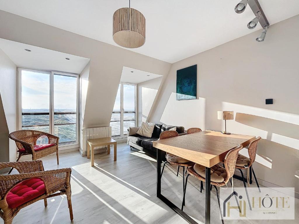 un salon avec une table, des chaises et un canapé dans l'établissement Sable & Horizon - Vue Mer - 7e étages, à Bray-Dunes