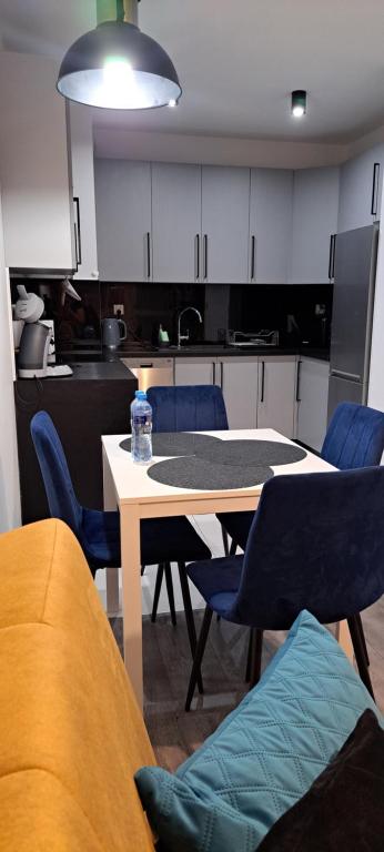 a kitchen with a table and blue chairs and a table and a table at Apartament Morski in Koszalin