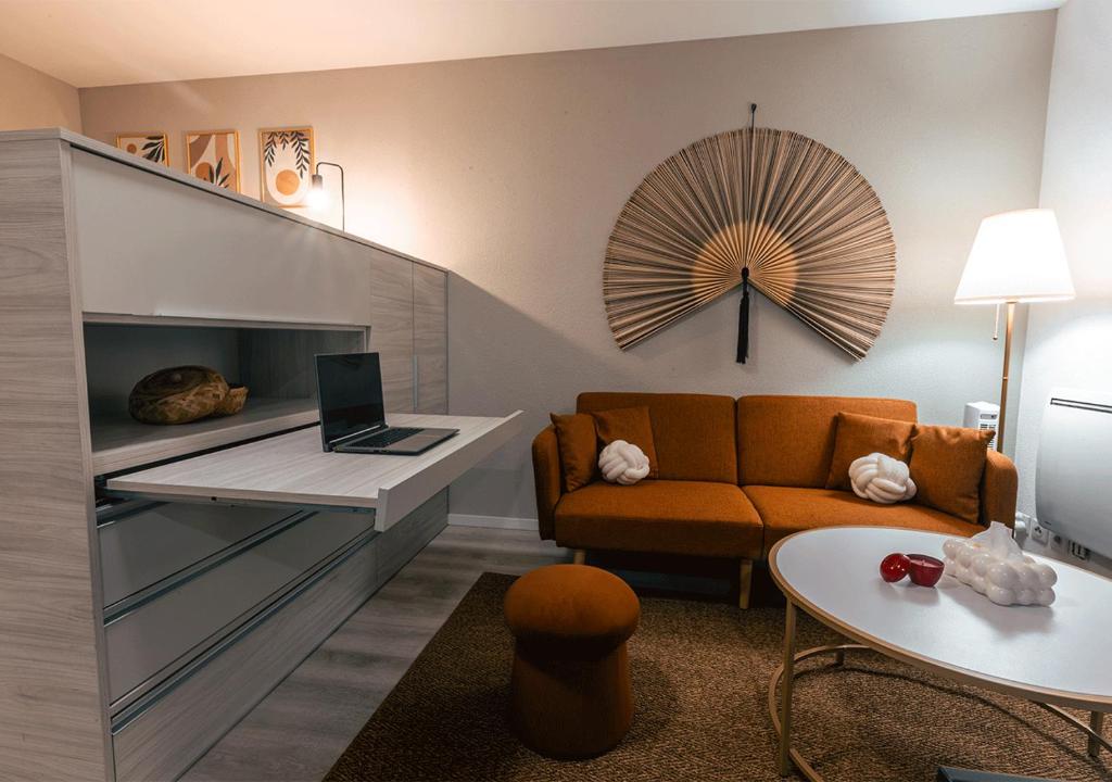 un salon avec un canapé et un bureau avec un ordinateur portable dans l'établissement l'évidence-Bâle-Aéroport-Lockeys, à Saint-Louis