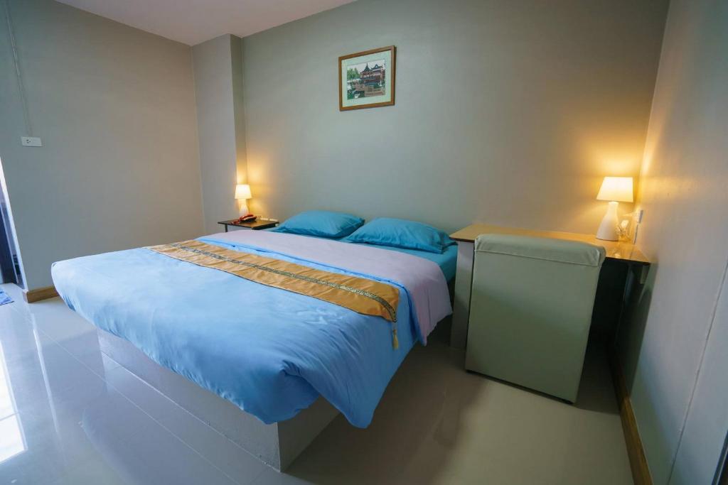 a bedroom with a bed with blue sheets and two lamps at Sritrang Place in Hat Yai