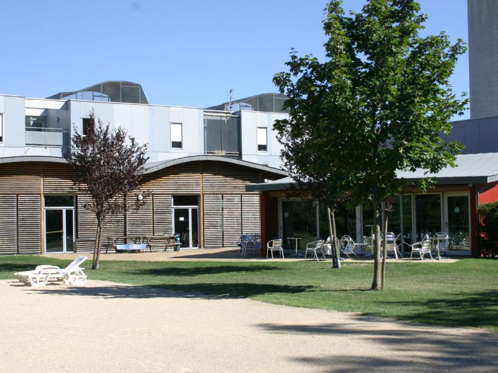 un bâtiment avec un arbre devant lui dans l'établissement Auberge de Jeunesse HI Grenoble, à Échirolles