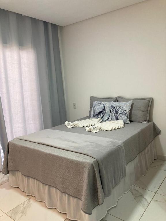 a bed in a white room with a window at Pousada Bella Flor in Baía Formosa