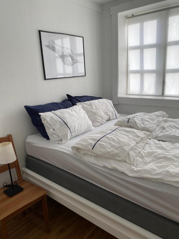 Una cama con sábanas blancas y almohadas azules en un dormitorio. en Vindmølle, en Stavanger