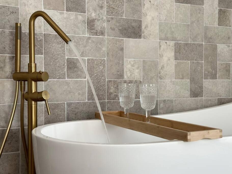 Soleá Apto en centro de Alhama في ألاما دي غرانادا: حوض استحمام به صنبور وكأسين للنبيذ