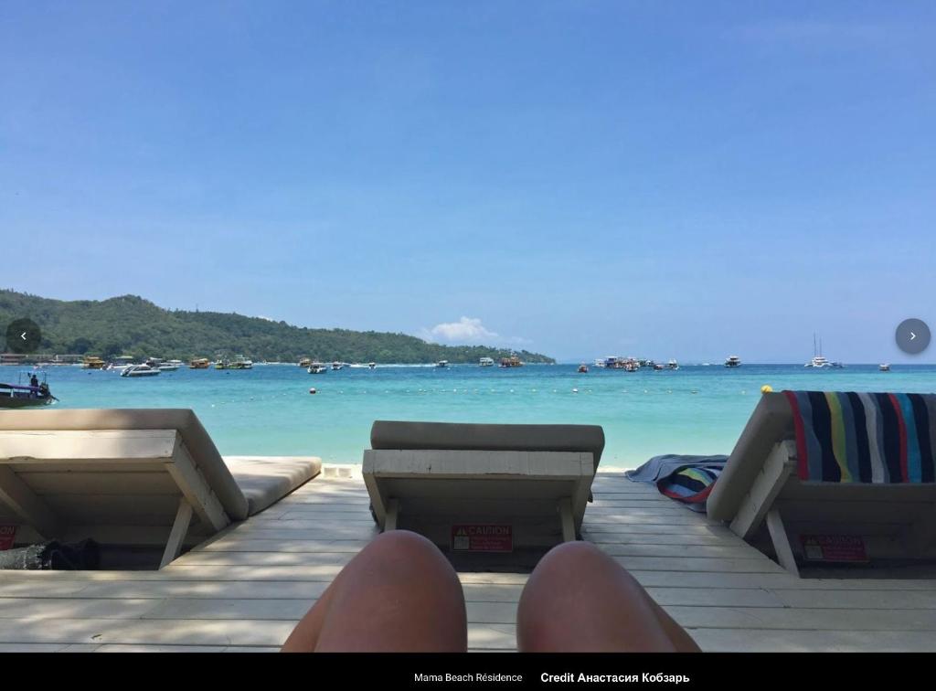 a person sitting on a dock near the ocean at Mama Beach Residence - Adults Only in Phi Phi Don