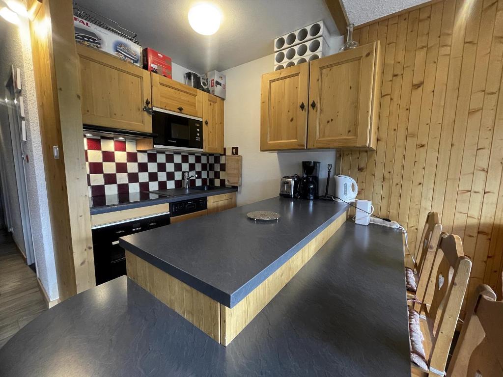 une cuisine avec un comptoir noir et des placards en bois dans l'établissement OURS BLANC 20 Appartement 4 pers avec belle vue, à La Clusaz